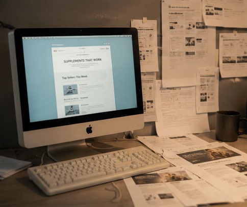 Landing-page printouts taped across an office wall, marked up in red pen